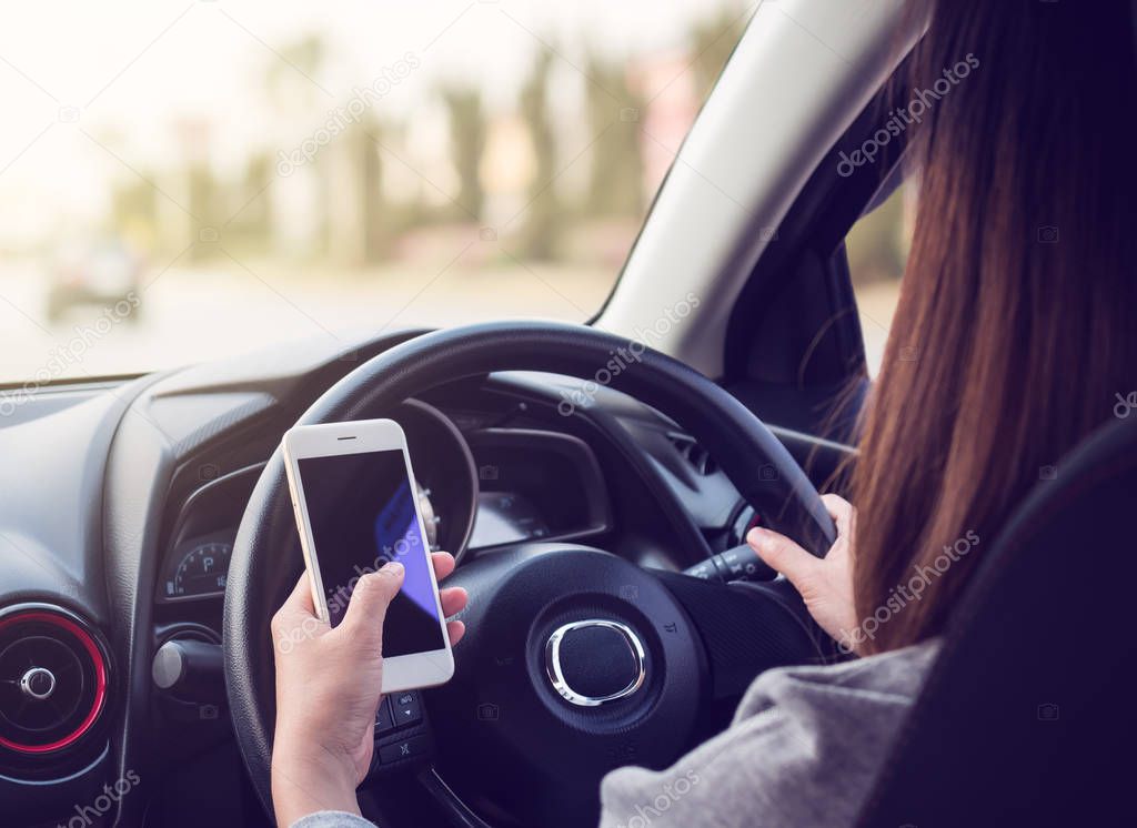 Woman driving and using smartphone on road
