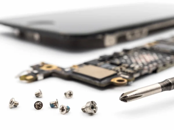 Schrauben und Schraubenzieher mit verschwommenen Smartphone-Komponenten — Stockfoto