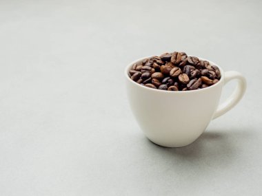 Yakın plan ve kenardan Tayland kahve çekirdekleri açık gri arka planda beyaz kahve fincanında fotokopi alanı için