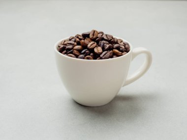 Yakın plan ve kenardan Tayland kahve çekirdekleri açık gri arka planda beyaz kahve fincanında fotokopi alanı için