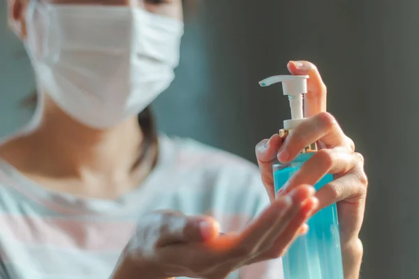 Woman wearing medical hygiene protective mask for health care from Coronavirus (COVID-19) quarantine at home cleaning hands with gel. Health care, quarantine and prevent from risk of Coronavirus (COVID-19) concept.