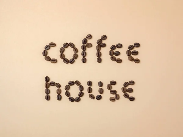コーヒーメニューやコーヒーショップの看板のためのライトブラウンの背景に文字で配置された焙煎コーヒー豆 — ストック写真