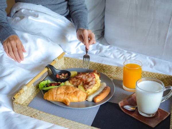 Asian woman eating French style breakfast on bed in hotel room. Food and healthy eating lifestyle concept.