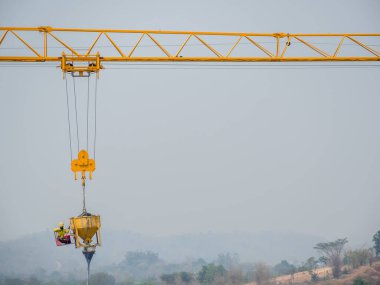 İnşaat işçileri, güvenlik riskleriyle beton döken makineleri kontrol etmek için vinçlerle asıldı..