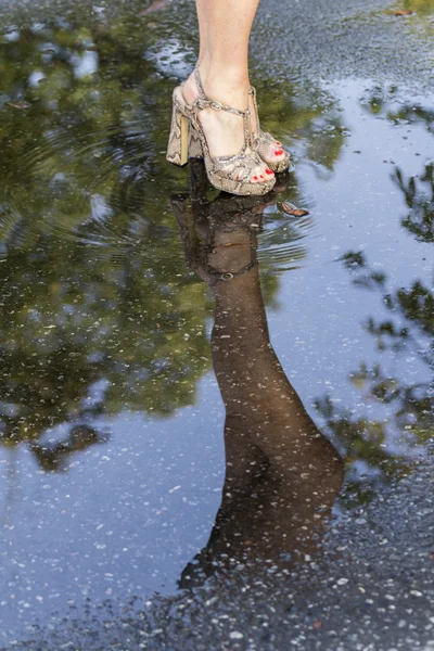 Los pies de las mujeres y su reflejo en el charco — Foto de Stock