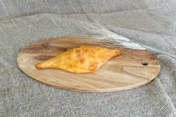 用小穗麦片在厨房的板子上把乌兹别克人的桑萨从松饼中挑出来 — 图库照片