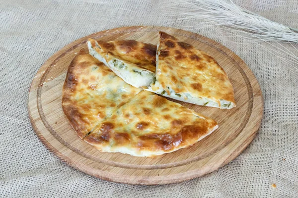   Çuval örtülü ahşap mutfak tahtasında peynirli ve soğanlı Asya geleneksel Khachapuri tortilla 'sı.