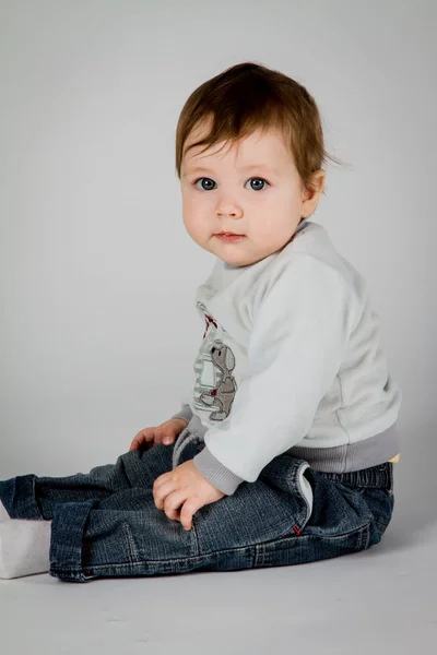 Kleine jongen zit op een witte achtergrond — Stockfoto