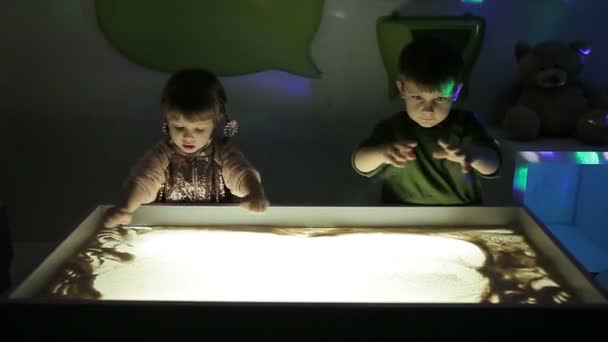 Kinderen tekenen met hun handen op het zand met verlichting — Stockvideo