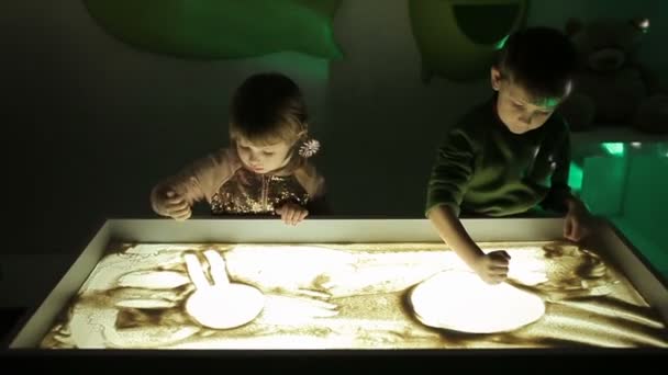 Kinderen tekenen met hun handen op het zand met verlichting — Stockvideo