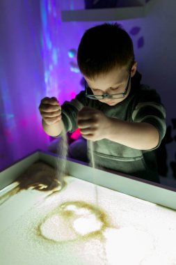 Çocuk kum kum çizer.