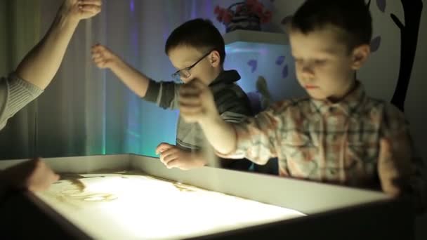 Kinderen tekenen met hun handen op het zand met verlichting — Stockvideo