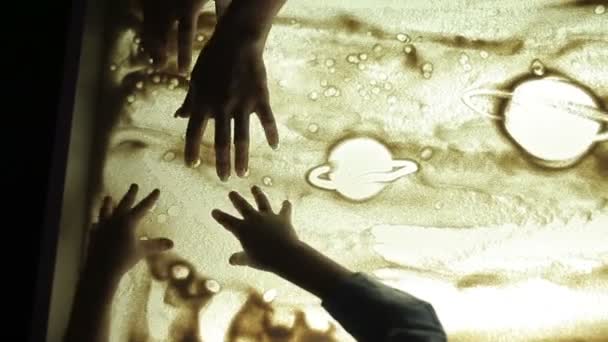 Hildren draw with their hands on the sand with illumination — Stock Video