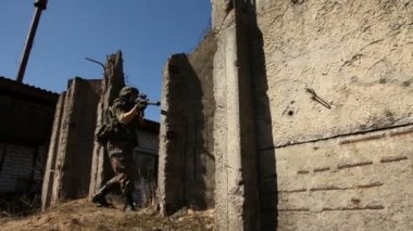 Genç askerlerin silahlı bir askeri ekipman ve silah ile harap bir ev şehir dışında olup olmadığını denetler. Asker silah ile savaş