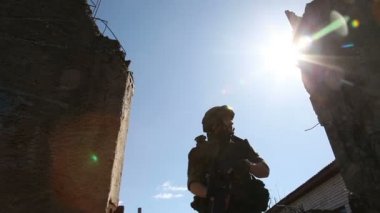 Genç askerlerin silahlı bir askeri ekipman ve silah ile harap bir ev şehir dışında olup olmadığını denetler. Asker silah ile savaş
