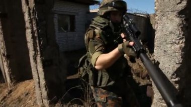 Askeri silah ile savaş. Genç askerlerin silahlı bir askeri ekipman ve silah ile şehir dışında harap bir ev inceler..
