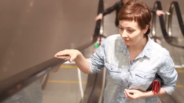 女の子がショッピング モールのエスカレーターを登る — ストック動画