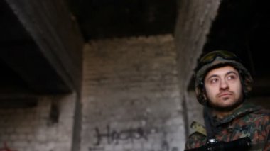 Silahlı genç askerler, teçhizatlı ve silahlı bir asker şehrin dışındaki harabe bir evi teftiş ediyor..