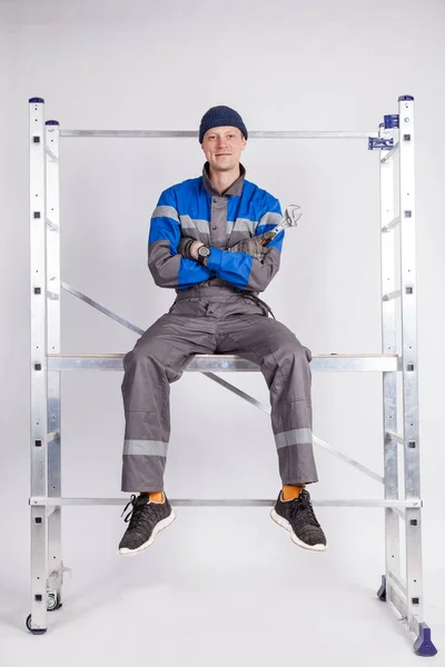 Budowniczy, Instalator siedzi na wysokości z narzędziem w jego rękach — Zdjęcie stockowe