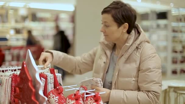 Woman chooses holiday Christmas presents in the mall. — Stockvideo