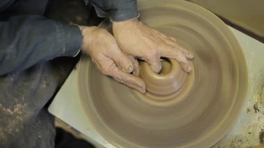 Potter çömlek çarkında çömlek aletleri olan bir kil ürün oluşturur, üst görünüm.