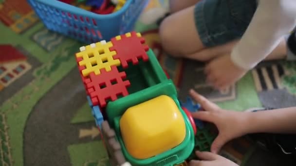 Çocuklar renkli plastik oyuncaklarla oynarlar. Arabaların oyunu. İki çocuk renkli plastik üreticileri topluyor. — Stok video