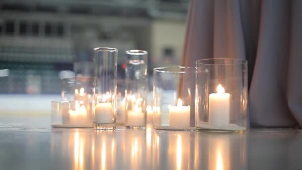 Velas blancas ardientes en un puesto de bombillas de vidrio en el hielo de la pista del estadio — Vídeos de Stock