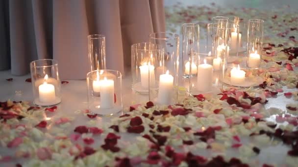Białe świece w szklanych kolbach, płatki róż leżą na lodzie — Wideo stockowe