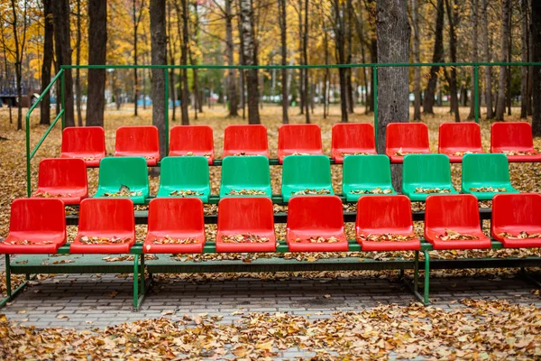 Κενά αθλητικά περίπτερα με κόκκινες και πράσινες θέσεις σε μια φθινοπωρινή ημέρα. — Φωτογραφία Αρχείου