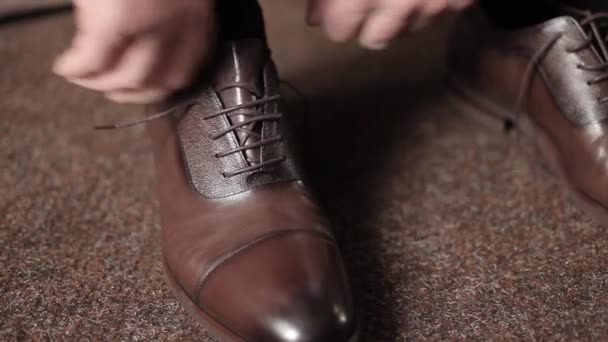 Επιχειρηματίας δένει κορδόνια σε καφέ μπότες σε ένα δωμάτιο. Ένας άντρας φοράει παπούτσια.. — Αρχείο Βίντεο