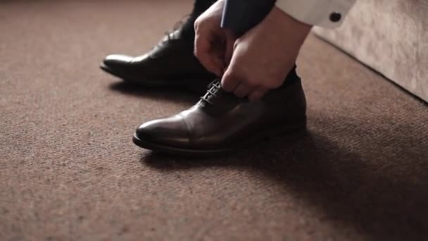 Businessman man ties shoelaces on brown boots in a room. A man wears shoes. — Stock Video