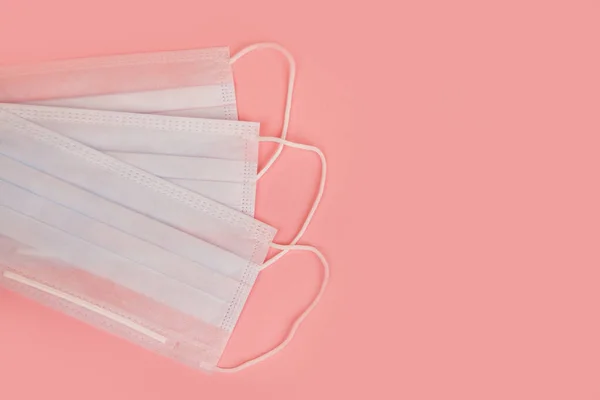 Pembe arka planda grip ve koronavirüse karşı korunmak için tıbbi maske. Virüsün yayılmasını önlemek ve salgın COVID-19.