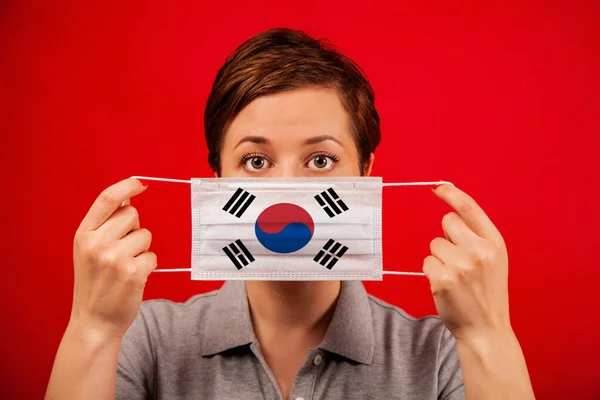 Coronavirus COVID-19 in South Korea. Woman in medical protective mask with the image of the flag of South Korea. The concept of preventing the spread of the epidemic and treating coronavirus.