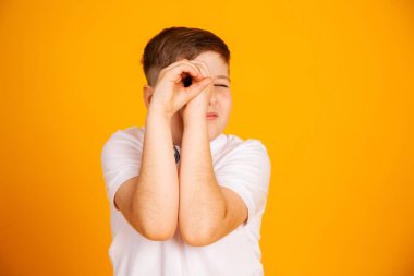 Çocuk dürbünden bakmış gibi görünüyor. Eller katlı.