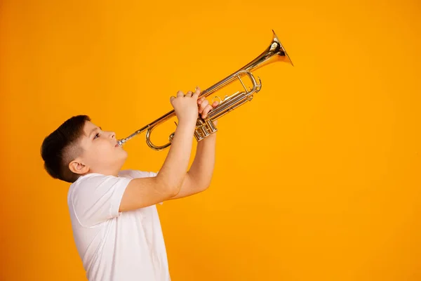 A boy plays the trumpet. Beautiful teenager boy plays trumpet musical instrument — Zdjęcie stockowe