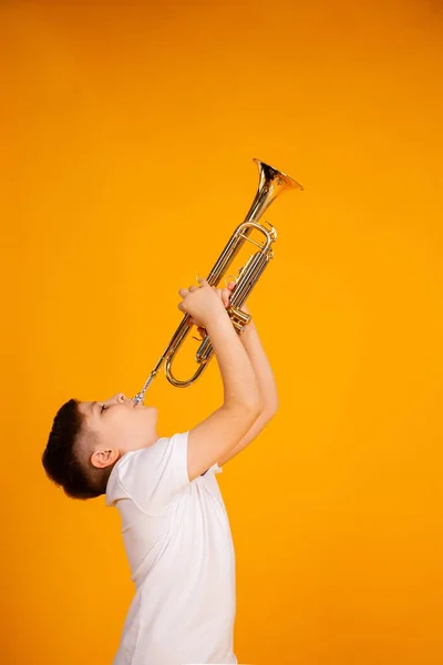 Poika soittaa trumpettia. Kaunis teini-ikäinen poika soittaa trumpettisoitinta — kuvapankkivalokuva