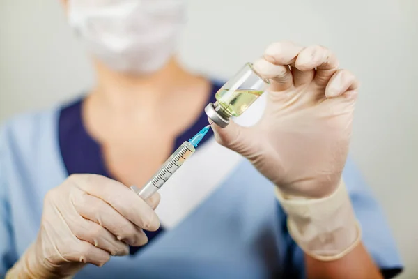 Çocuk ve yetişkinleri aşılamak için grip, kızamık, koronavirüs COVID-19 aşısına karşı aşılanmış şırınga iğnesi ile nitril eldivenli bir doktor ya da hemşirenin eli