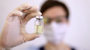 Azot eldivenli bir doktor ya da hemşire elinde grip, kızamık, koronavirüs COVID-19 'a karşı aşılanmış bir aşı tutuyor.