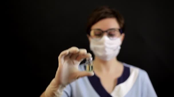 Врач или медсестра в нитрильных перчатках держит в руке вакцину против гриппа, кори, коронавируса COVID-19 для — стоковое видео