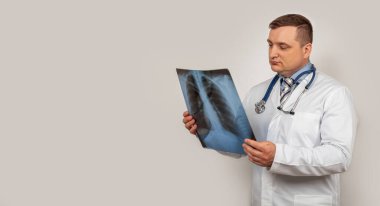 Erkek bir doktor göğüs röntgenini inceler ve inceler. Zatürree belirtileriyle bir insanın akciğerlerinin görüntüsü..