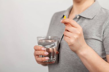 Kadın eli hapları ve su stoğunu tutuyor. Sağlık hizmeti, tıbbi destek konsepti. İyileşmek için elinde ilaç tutan hasta kız.