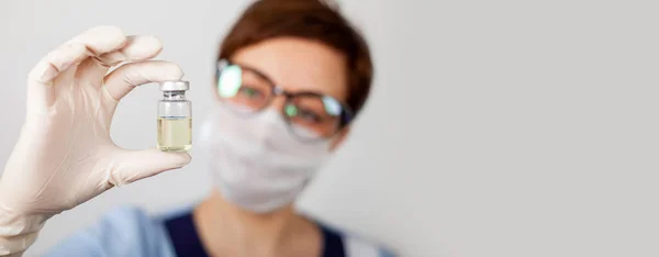 Azot eldivenli bir doktor ya da hemşire elinde grip, kızamık, koronavirüs COVID-19 'a karşı aşılanmış bir aşı tutuyor.