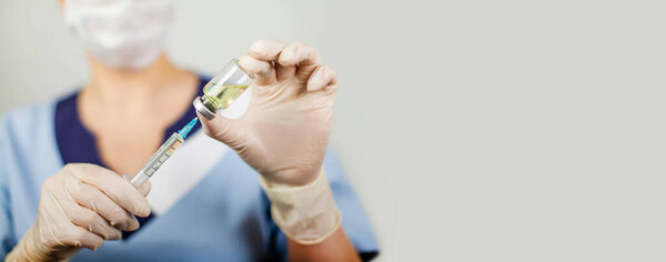 Hand of a doctor or nurse in nitrile gloves with a syringe needle vaccinated against influenza, measles, coronavirus COVID-19