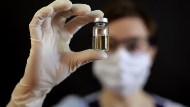 En läkare eller sjuksköterska i nitrilhandskar håller ett vaccinerat vaccin i handen — Stockvideo