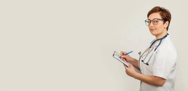 Kadın doktor kalemle yazar tablete bir belge yazar, tıbbi geçmiş yazar. Sağlık ve ilaç kavramı.