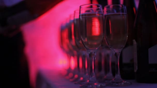 Офіціант вливає шампанське в окуляри на святкуванні. вечірка кольорових вогнів . — стокове відео