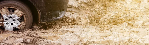 The car got stuck on a dirt road in the mud. Wheel of a car stuck in the mud