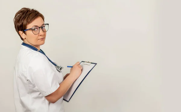 Ärztin schreibt mit einem Stift ein Dokument auf einem Tablet, schreibt eine Krankengeschichte. Das Konzept der Gesundheitsfürsorge, Medizin — Stockfoto