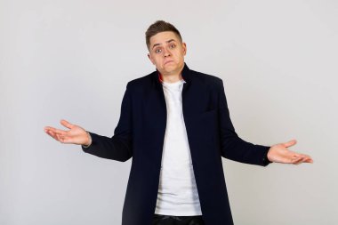 Çekici genç bir erkek, kaybolmuş bir ifadeyle omuz silker..