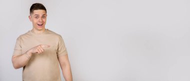 Yakışıklı ve güçlü bir genç adam yüzünde şaşkın bir ifadeyle parmağını sağa doğru gösteriyor..